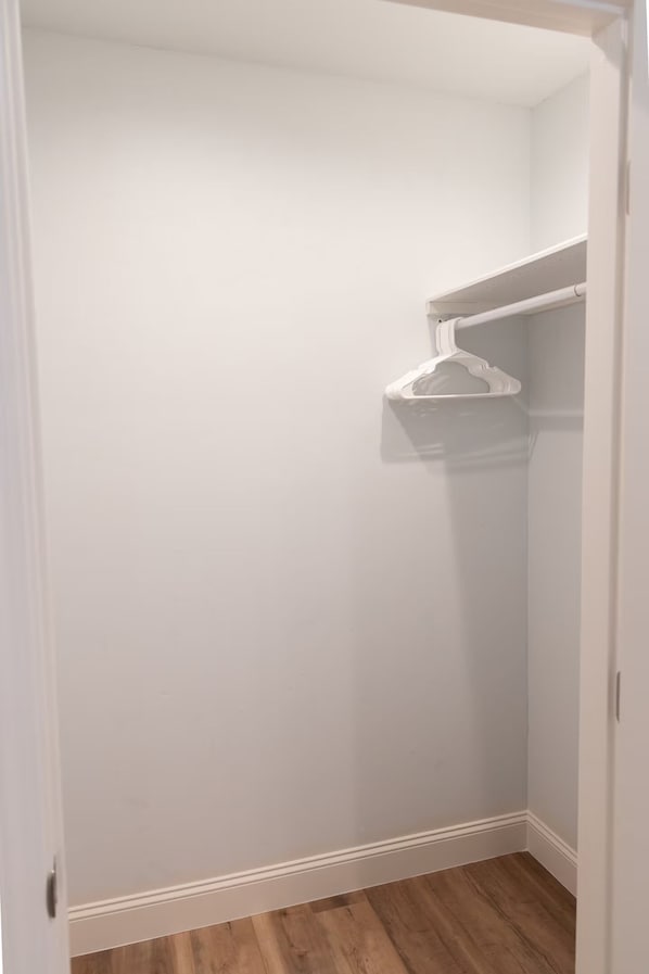 A closet with white walls and a wooden floor. - Cozy 2-bedroom house in tranquil Clovis with AC (Clovis)