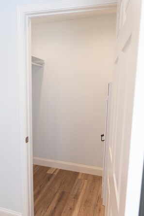 A narrow hallway with a wooden floor and a white door on the right.