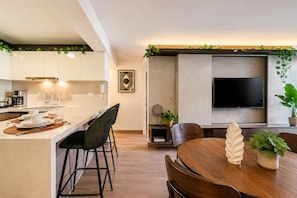 A modern kitchen with a dining area, a flat-screen TV, and a potted plant. - Suite ejecutiva Piscina y Gym San Isidro (San Isidro)