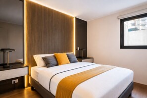Ein modernes Hotelzimmer mit einem großen Bett, Nachttischlampen und Blick auf die Stadt durch ein Fenster.