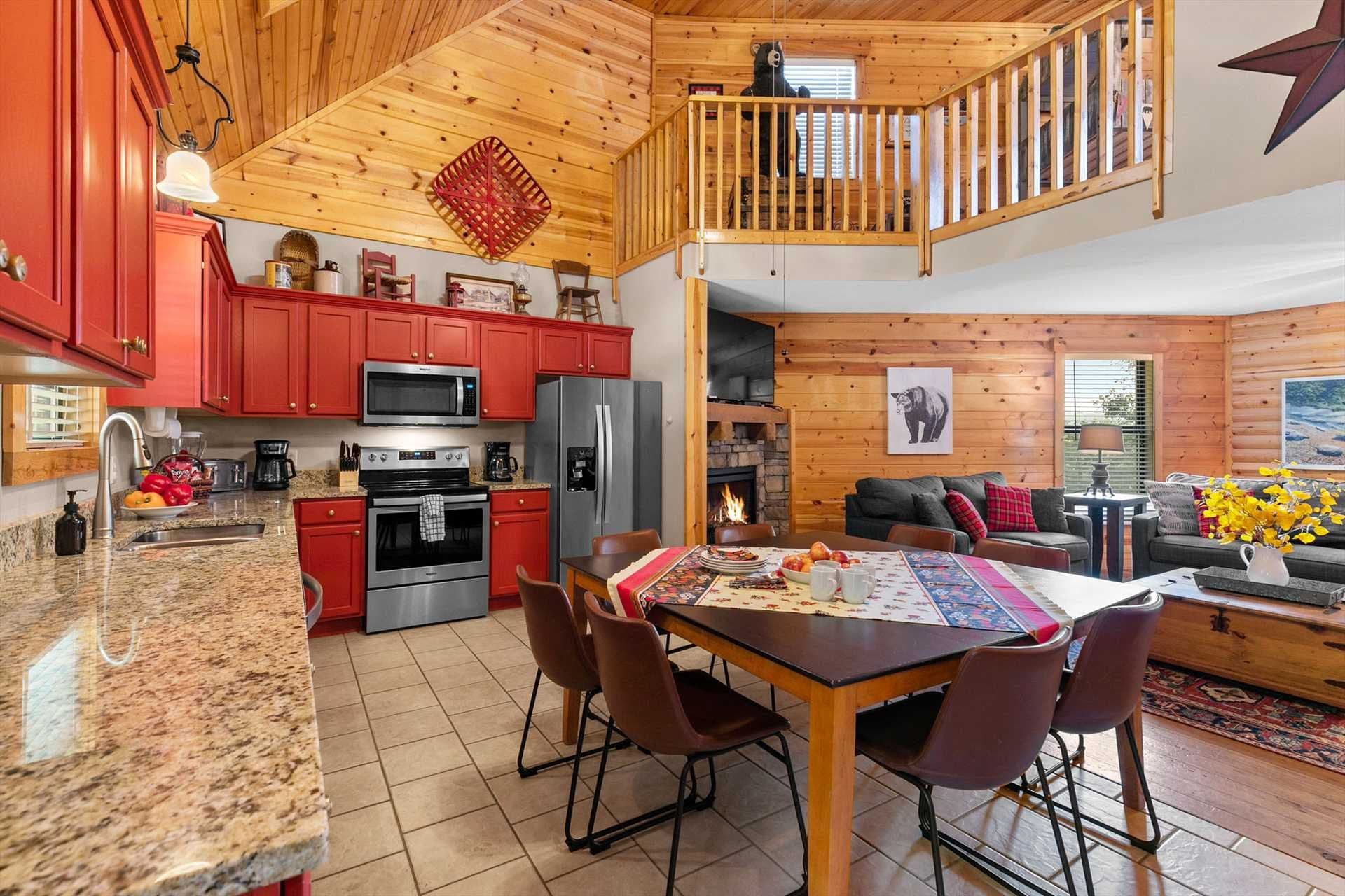 A spacious living area with a dining table, chairs, a fireplace, and a balcony with a wooden railing.