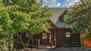 A log cabin with a welcoming sign, a porch, and a red chair.