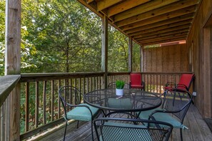 An outdoor wooden deck with a round metal table and chairs, surrounded by a wooden railing. - Incredible 3 Level Luxury Cabin! 4 Bedroom Suites, 2 Living Areas, 3 Pools-21 (Branson)