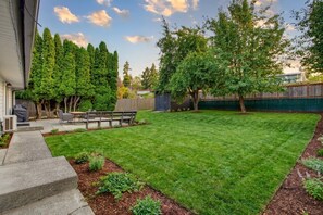 A backyard with a lawn, a patio with outdoor furniture, and a variety of trees. - Three bedroom  in United States of America, Kent (Kent)