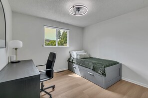 A bedroom with a bed, desk, chair, and a window with a view of trees. - Three bedroom  in United States of America, Kent (Kent)