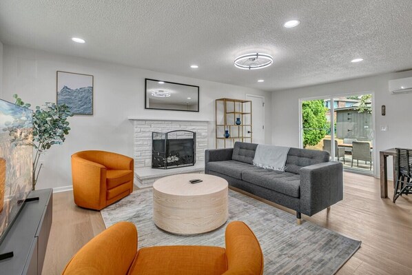 A modern living room with a fireplace, a round coffee table, and two orange armchairs. - Three bedroom  in United States of America, Kent (Kent)