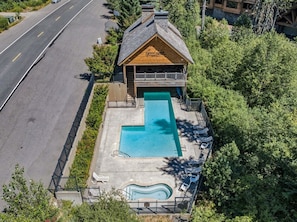 A building with a swimming pool, a covered deck, and a road in the background. - Elk Cove Condo 403 at South Grand Lodge | 2BR + Queen Loft, 3 Baths, Mt. Hood Peek (Government Camp)