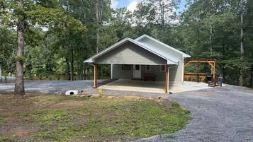 A single-story building with a covered porch, a wooden deck, and a bench.