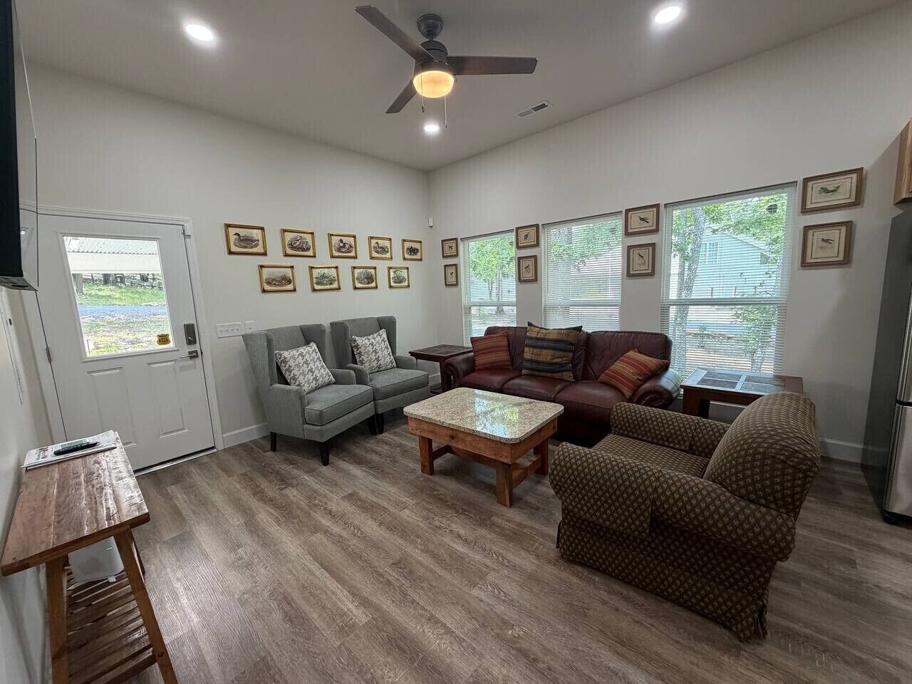 A living room with a ceiling fan, a gray sofa, a brown patterned armchair, and a coffee table.