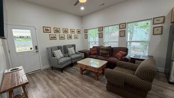A living room with a ceiling fan, a gray sofa, a brown patterned armchair, and a coffee table.