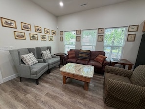 A living room with two sofas, a coffee table, and framed pictures on the wall. - Brand-New Riverfront Escape with Kayak Access (Mentone)