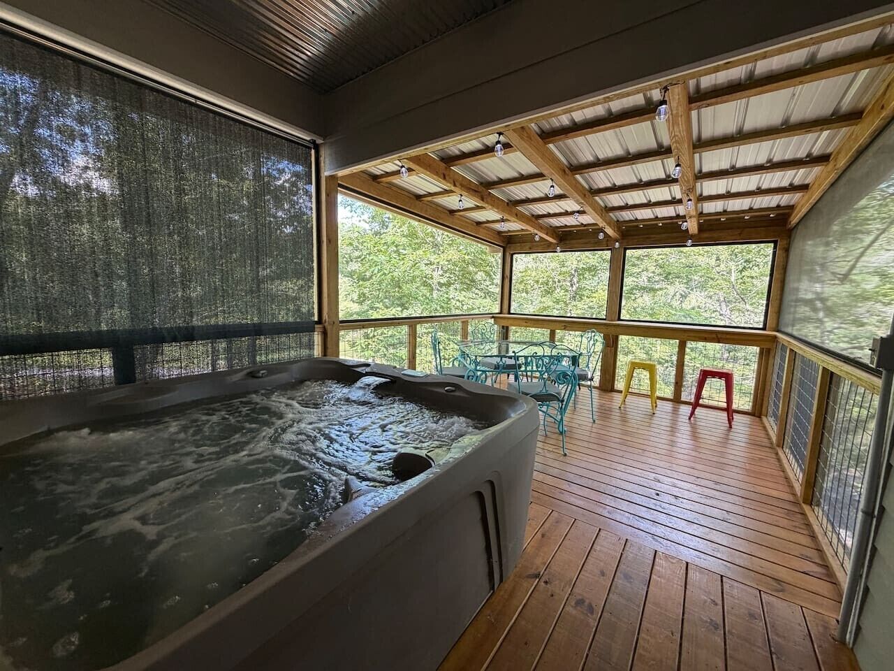 A hot tub in a covered outdoor area with wooden flooring and metal railings.