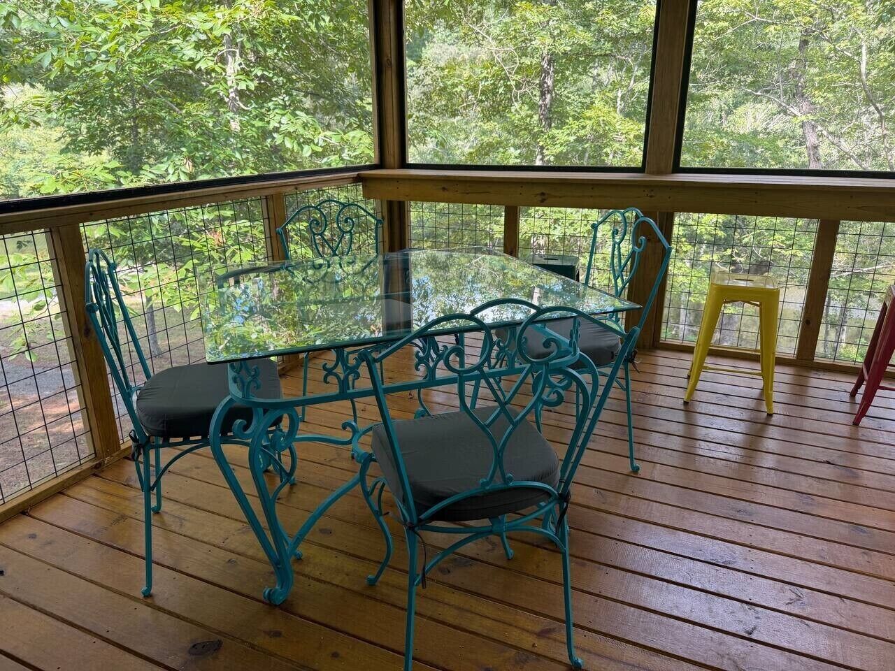 Une terrasse extérieure en bois, avec une table en verre et des chaises en métal.