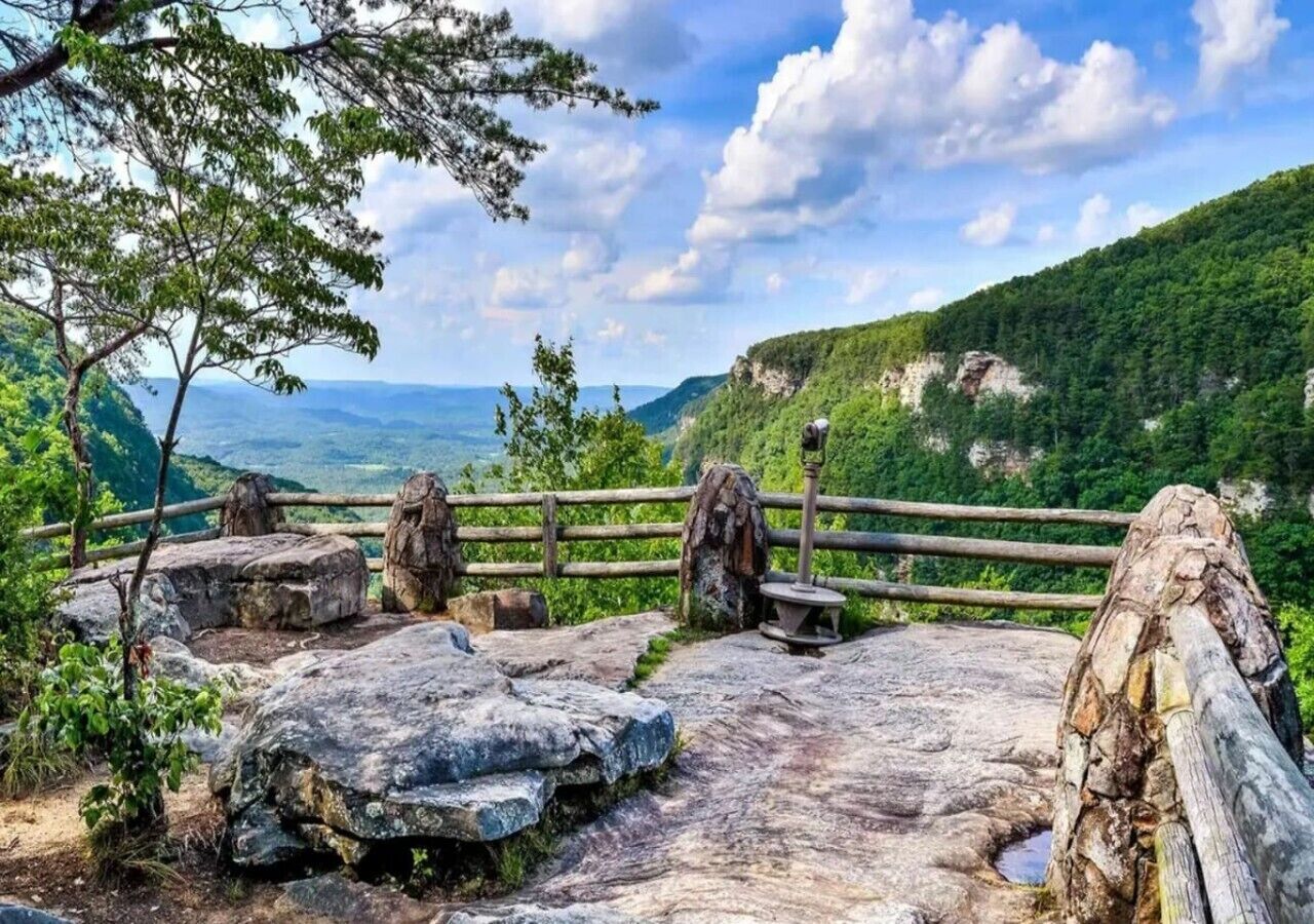 A natural landscape with a wooden fence, large rocks, and a bench.
