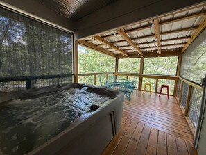 A hot tub on a wooden deck with a covered area and chairs.