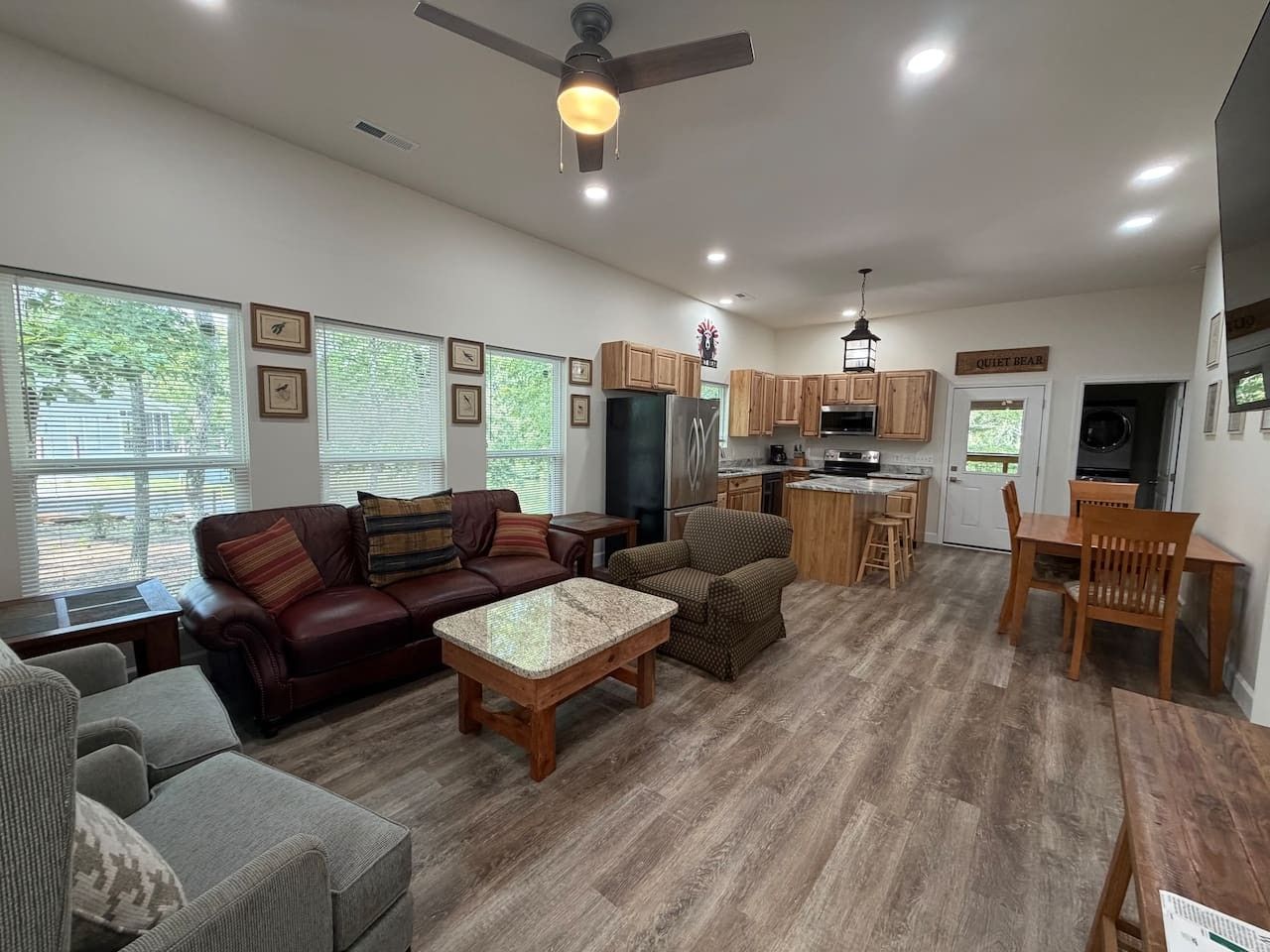 A spacious living room with a fireplace, a dining area with wooden furniture, and a kitchen with wooden cabinets.