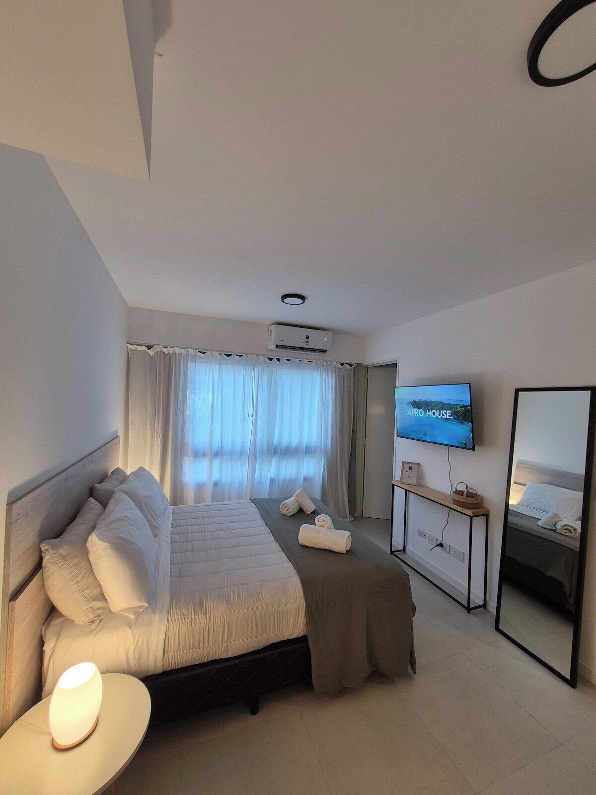 Een hotelkamer met een bed, een televisie, een nachtkastje en een spiegel.