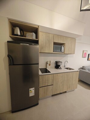 Eine kleine Küche mit Kühlschrank, Mikrowelle und Spüle.