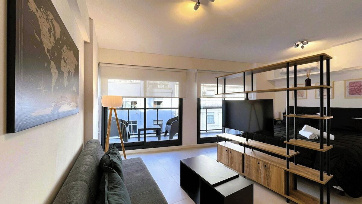 A modern living room with a sofa, a coffee table, a TV, and a bookshelf.