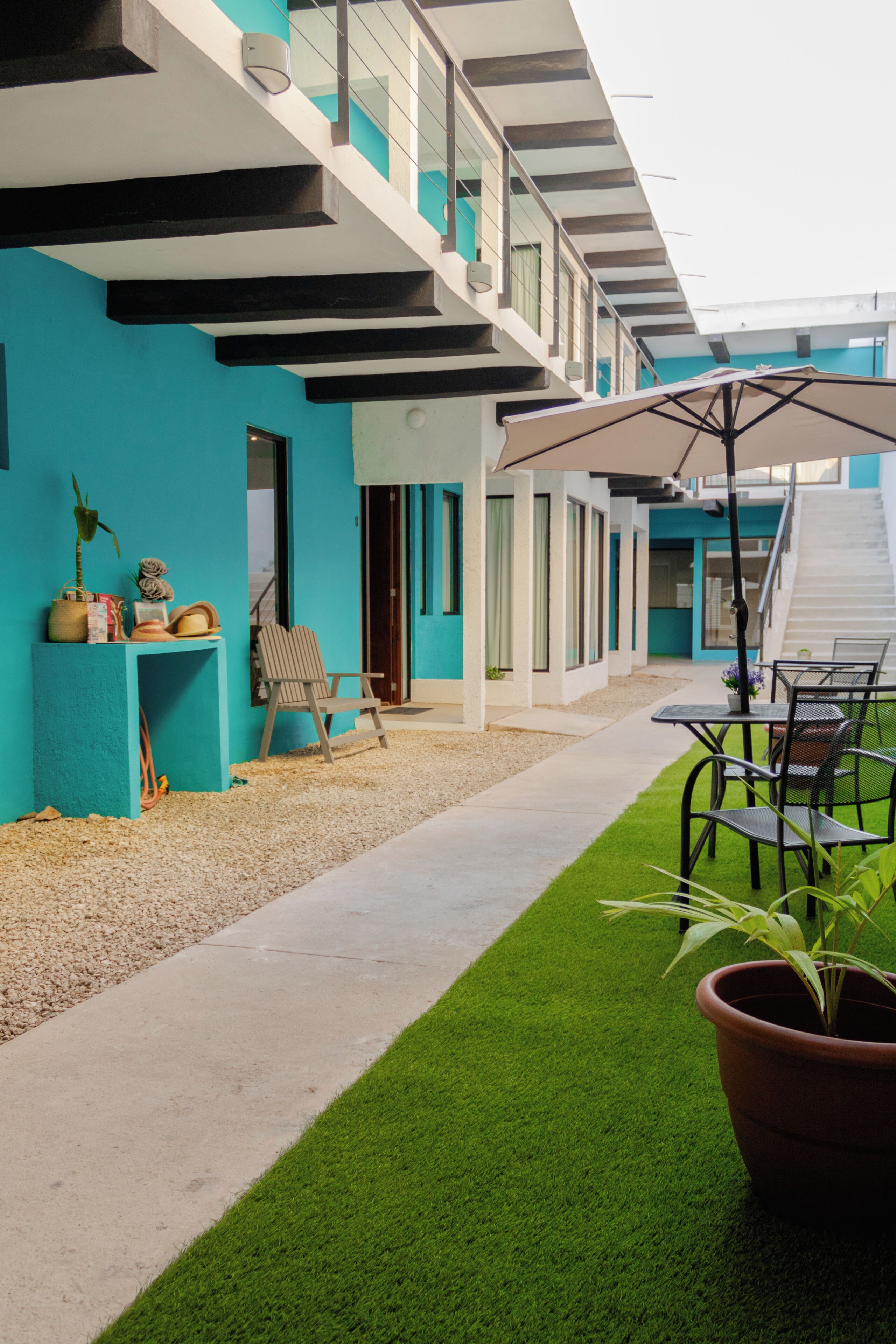 Un edificio moderno con una escalera, asientos exteriores y un pequeño jardín.