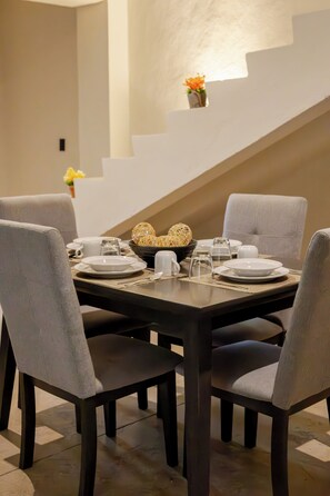 Un comedor con una mesa rectangular dispuesta para cuatro personas, rodeada de sillas tapizadas.