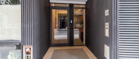 A modern hotel entrance with a glass door, a number '2063' sign, and a metal security gate.
