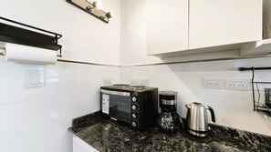 A kitchen with a black countertop, a toaster, a coffee maker, and a kettle. - The Ultimate Studio in Palermo (Buenos Aires)