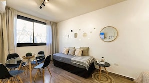 A bedroom with a bed, a round mirror, a small table with a sign, and a window with curtains. - The Ultimate Studio in Palermo (Buenos Aires)