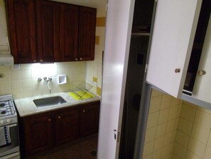 A kitchen with wooden cabinets, a white sink, and a stainless steel refrigerator. - Spacious Apartment in Prime Recoleta (Buenos Aires)