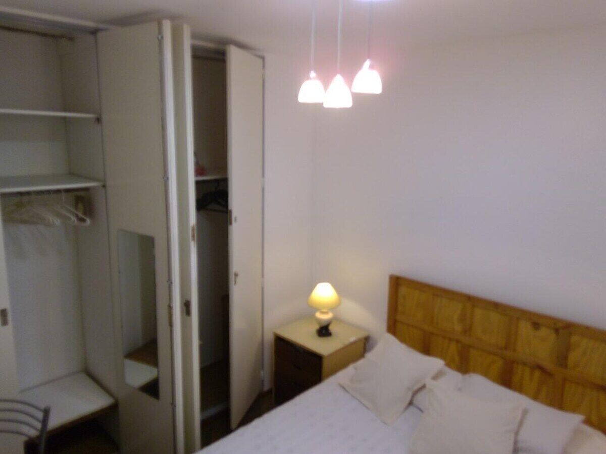 Un dormitorio con cama, lámpara de noche y armario.