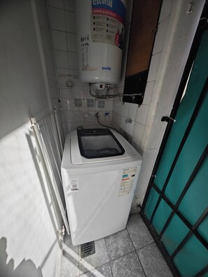 A compact laundry room with a washing machine and a water heater. - Departamento en calle Guemes (Buenos Aires)