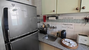 Cozinha com geladeira de aço inoxidável, pia e máquina de café.