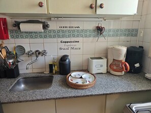 Une cuisine équipée d’un évier, d’une machine à café, d’un grille-pain et d’un crédence décorative.