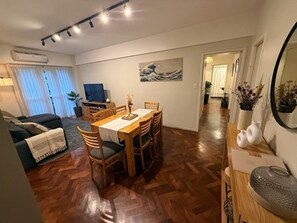 A modern living space with a dining area, a sofa, a TV, and a hallway leading to another room. - Elegant & Spacious Apartment in Downtown BA (Buenos Aires)