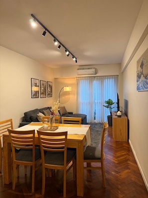 A dining area with a table and chairs, a sofa, and an air conditioning unit. - Elegant & Spacious Apartment in Downtown BA (Buenos Aires)