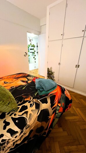A bedroom with a bed, a wardrobe, and a door leading to another room. - Jungle Chic in Palermo · Vibrant & Unique (Buenos Aires)