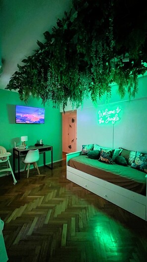 A room with a bed, a desk, a chair, a TV, and a neon sign. - Jungle Chic in Palermo · Vibrant & Unique (Buenos Aires)