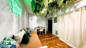A room with a sofa, a dining table, and a hanging plant. - Jungle Chic in Palermo · Vibrant & Unique (Buenos Aires)