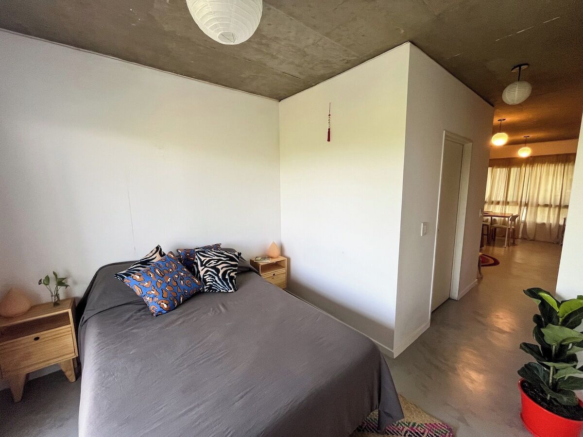 Une chambre à coucher moderne avec un lit, des tables de chevet et une plante en pot.