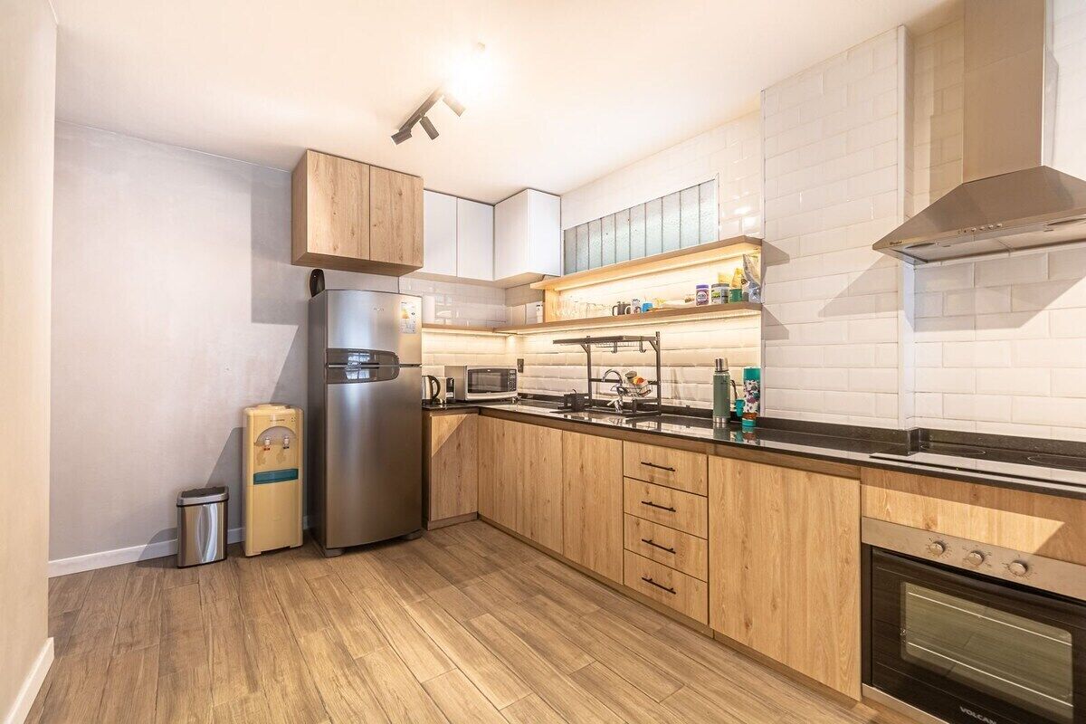 Une cuisine moderne avec des meubles en bois, un réfrigérateur en acier inoxydable, un four à micro-ondes et un four encastré.