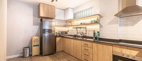 Une cuisine moderne avec des meubles en bois, un réfrigérateur en acier inoxydable, un four à micro-ondes et un four encastré.