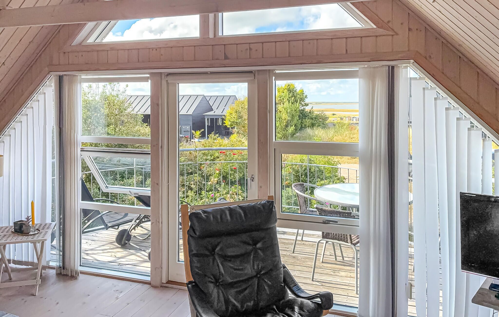 A room with a large sliding glass door leading to an outdoor patio with a table and chairs.