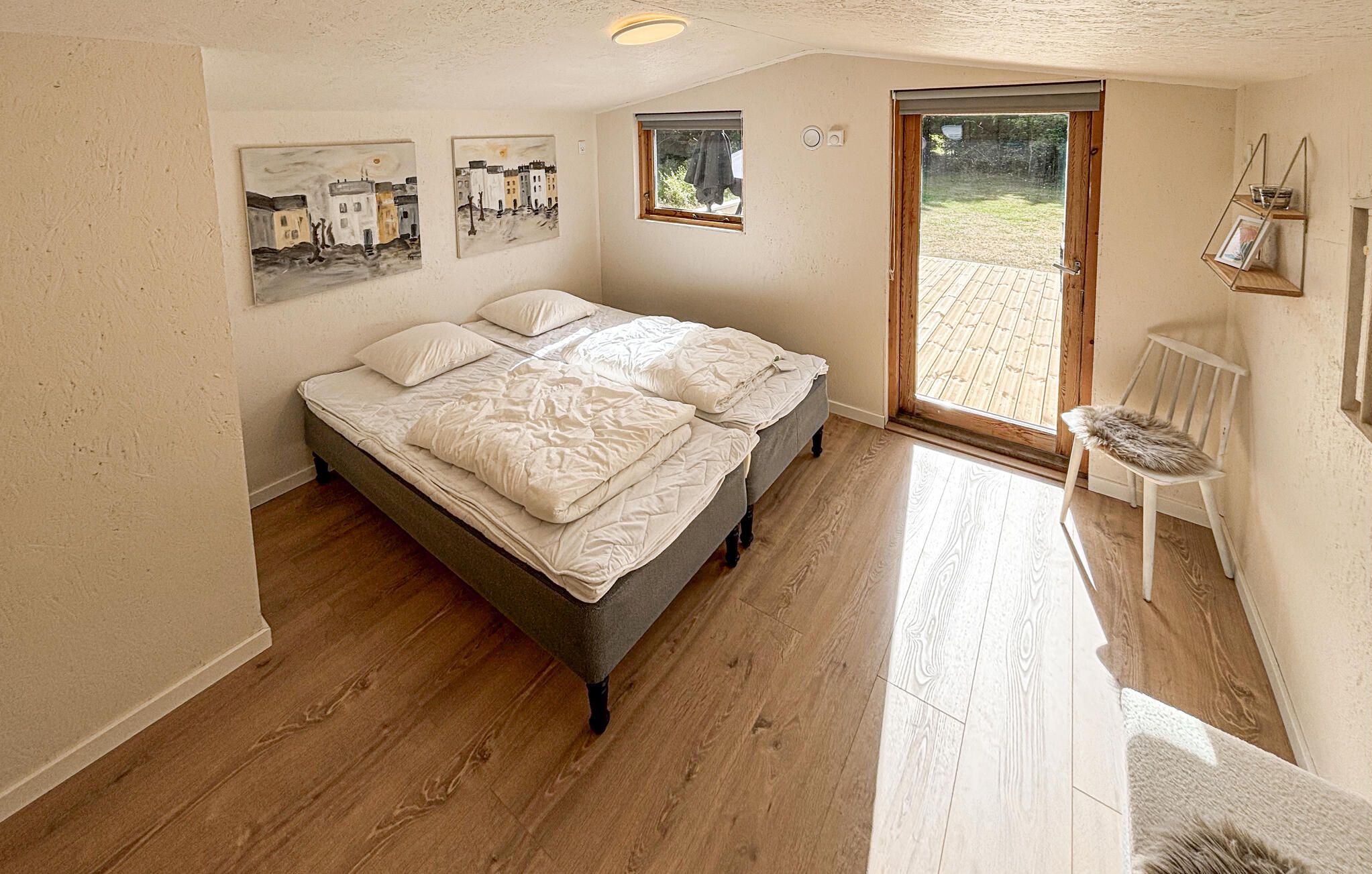 Une chambre avec un grand lit, deux fenêtres et une vue sur l’extérieur.
