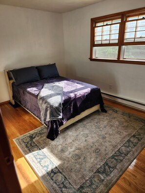 A bedroom with a bed, a window, and a patterned rug.