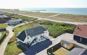 Een landgoed aan de kust met een groot huis, een opvallende trap, een klein bijgebouw en uitzicht op zee.