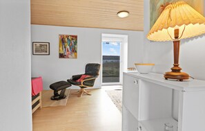 A room with a wooden ceiling, a chair, a table with a lamp, a painting, and a window with a view. - Nice home in Thyborøn with WiFi (Thyborøn)