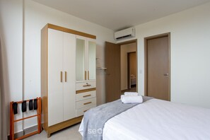 A bedroom with a bed, a wardrobe, a mirror, and an air conditioning unit. - Apt w/ 3 Suites in a Condo w/ a Pool Vll0010 (Maraú)