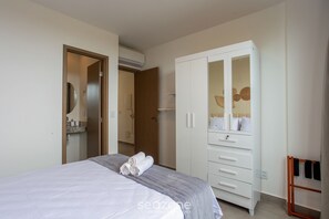A bedroom with a bed, a wardrobe, a mirror, and a towel rack. - Apt w/ 3 Suites in a Condo w/ a Pool Vll0010 (Maraú)