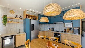 A modern kitchen with a dining area, featuring a built-in refrigerator, a microwave, a stove, and a sink. - Apto Encantador Cerca del mar en Marau Vll0107 (Maraú)