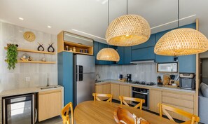 Uma cozinha moderna com área de jantar, com geladeira embutida, micro-ondas, fogão e pia.